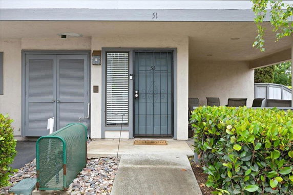 Front view of a house entrance with a covered porch and double doors.