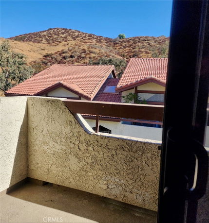 View of hillside and rooftops from a balcony.