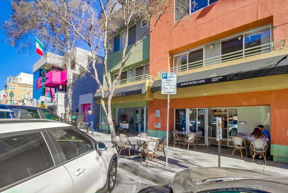 Front view of a colorful street-level building with restaurants and outdoor seating.