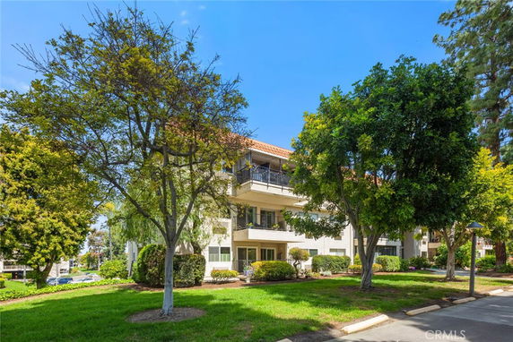 Front view of a multi-story building with balconies and a tiled roof.