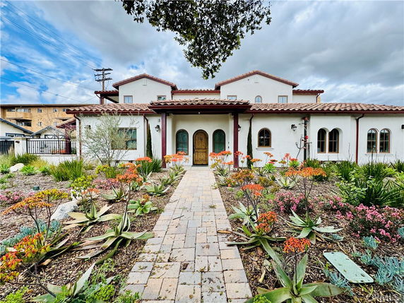 Front view of a two-story house with a tiled roof and arched windows.
