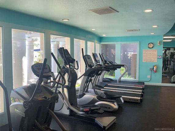 Room with fitness equipment including treadmills and elliptical machines.
