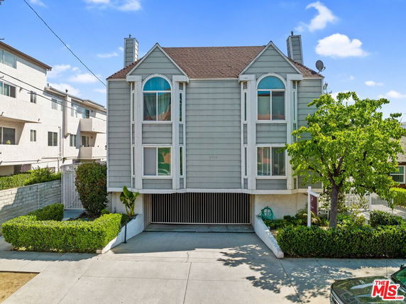 Front view of a multi-story residential building with bay windows and a pitched roof.
