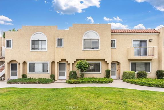 Front view of a two-story townhouse with arched windows and balconies.