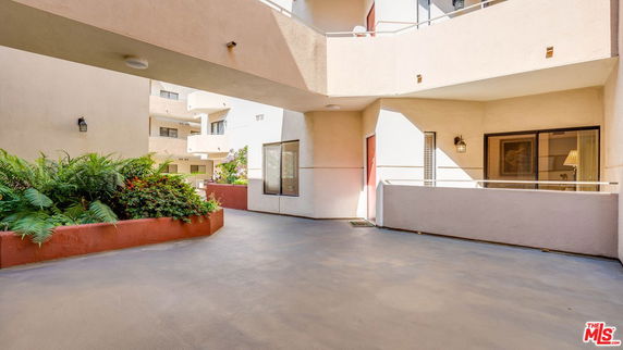 Exterior view of a multi-story building with a balcony and landscaped area.