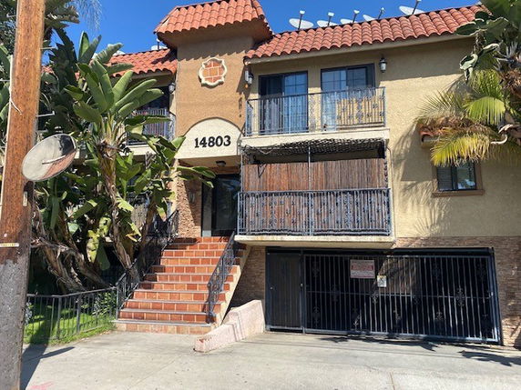 Front view of a two-story building with balconies and tiled roof.