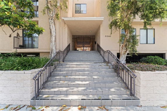 Front view of a multi-story building with entrance steps and railing.