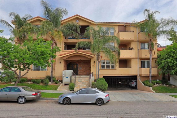 Front view of a multi-story apartment building with balconies and a garage entrance.