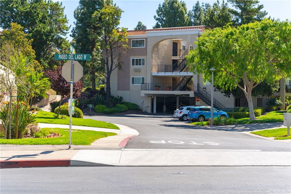 Front view of a multi-story residential building with a staircase and parking area.
