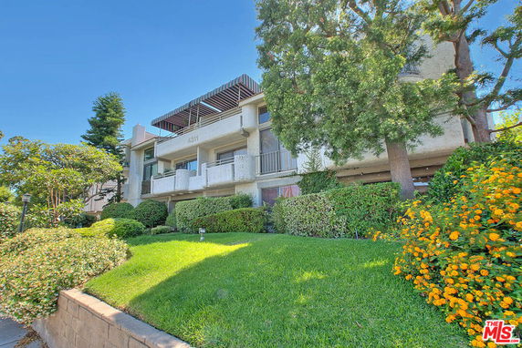 Front view of a multi-story building with balconies and a landscaped foreground.