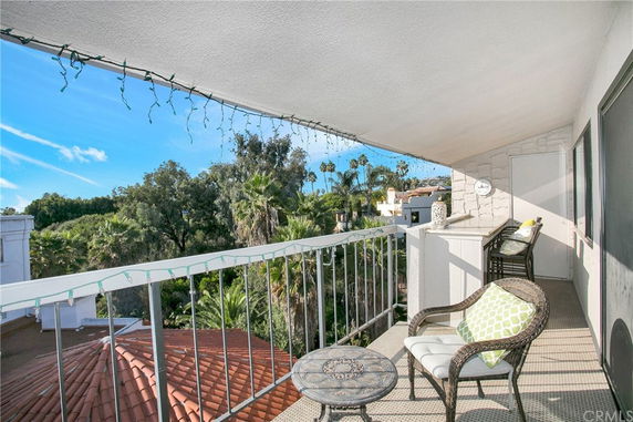 Balcony view overlooking trees and rooftops with outdoor seating.