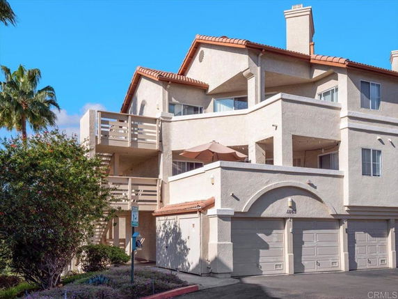 Front view of a multistory building with balconies and garages.