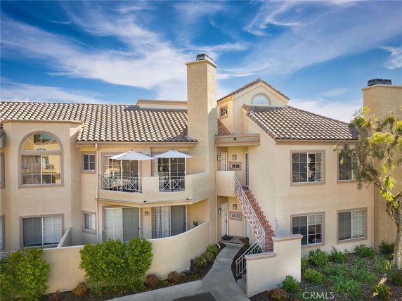 Front view of a multi-story house with balconies and a tiled roof.