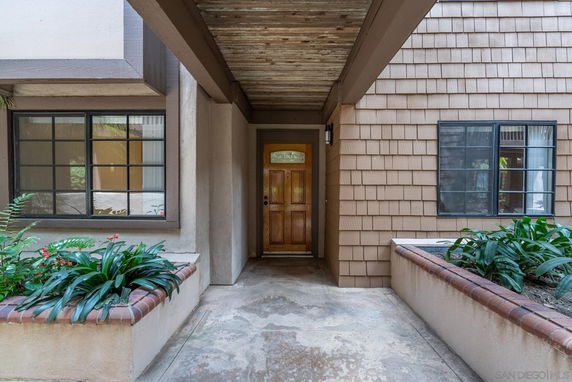 Front view of a house entryway with wooden door and surrounding windows.