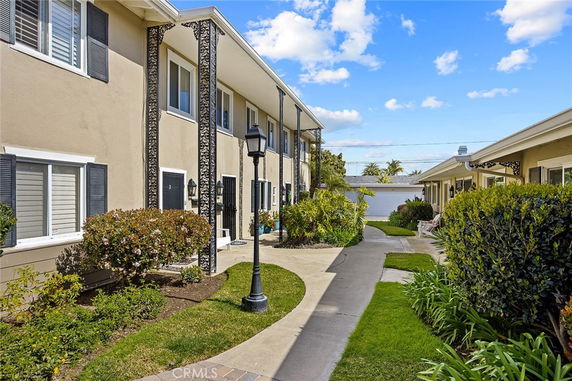 Front view of a two-story residential building with decorative pillars and landscaped surroundings.
