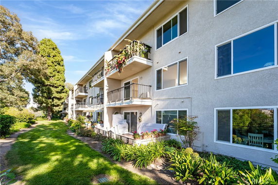 Side view of a multi-story residential building with balconies and surrounding greenery.
