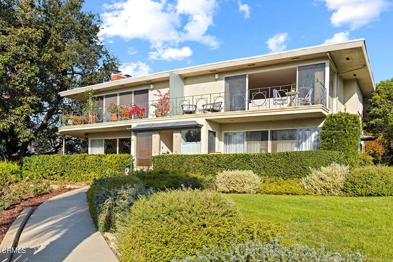 Front view of a two-story house with balconies and large windows.