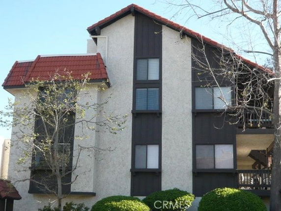 Front view of a multi-story residential building with a red-tiled roof and stucco exterior.