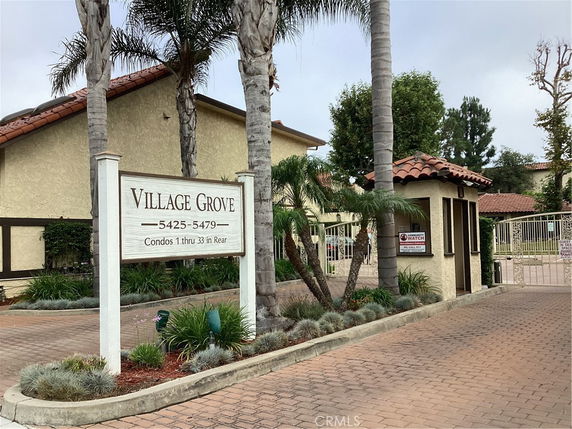 Front view of a residential complex entrance with sign and driveway.