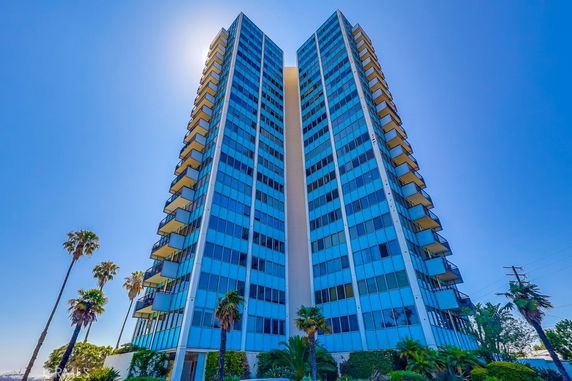 Front view of a tall modern apartment building with glass balconies.