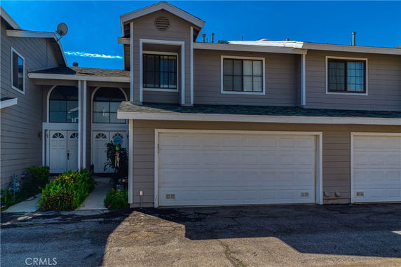 Front view of a two-story house with a garage and decorative entrance.