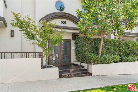 Front view of a house entrance with decorative glass doors and surrounding greenery.