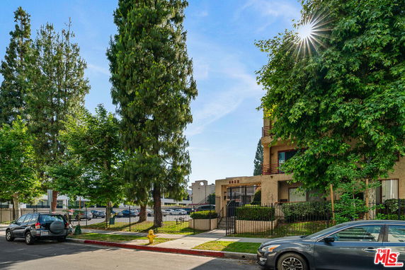Front view of a multi-story residential building with balconies and a gated entrance.