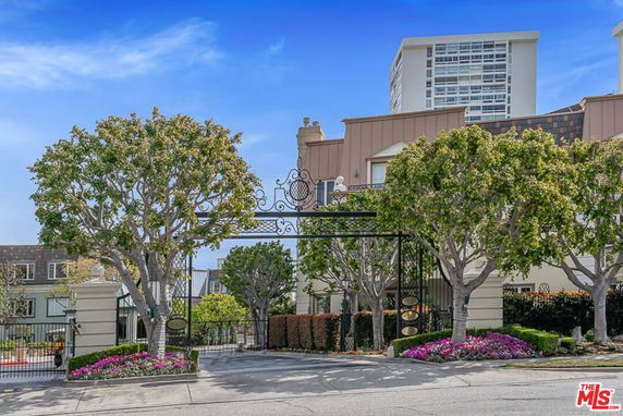 Front view of a gated residential complex with trees and landscaping