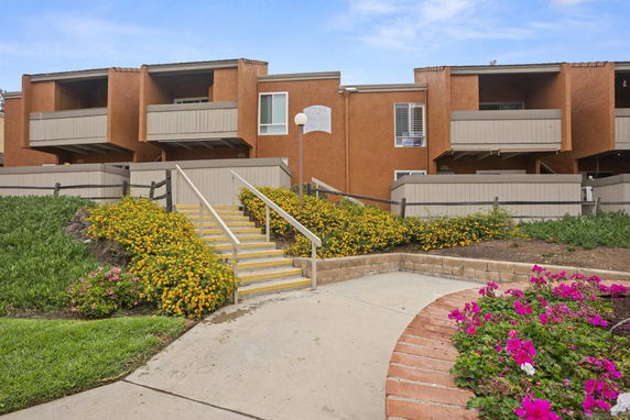 Front view of a multi-story apartment building with balconies and steps leading up.