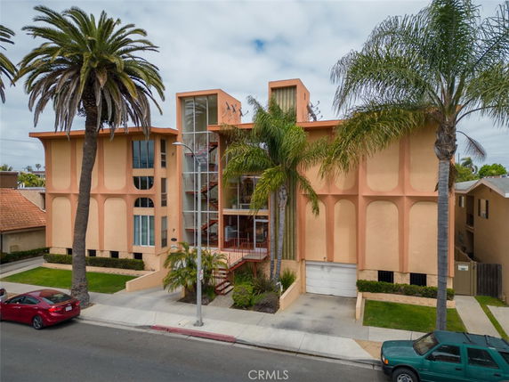 Front view of a multi-story building with large windows and palm trees.