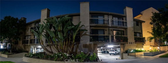 Front view of a multi-story building with gated parking area at night.