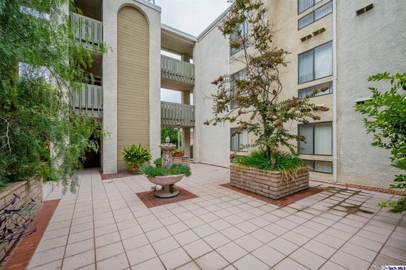 Front view of a multi-story building with balconies and a central courtyard with plants.