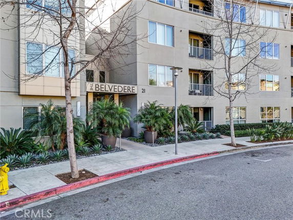 Front view of a multi-story residential building with balconies and landscape.
