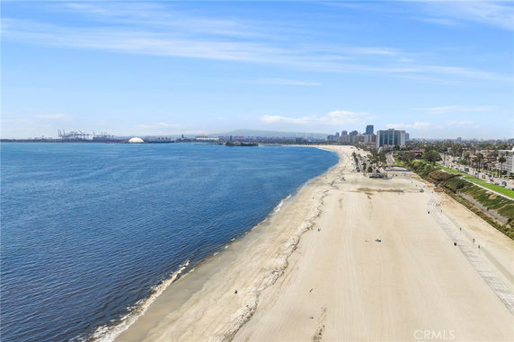 Panoramic view of a coastal beach with a cityscape in the background.
