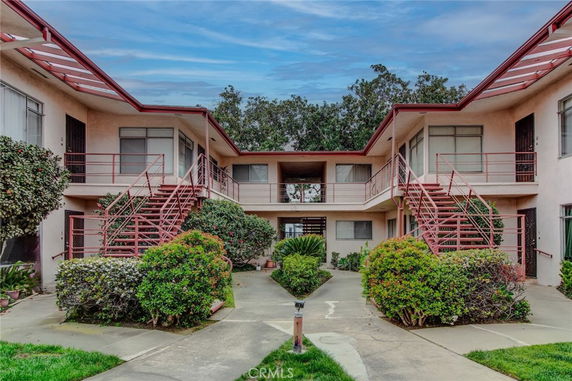 Front view of a two-story apartment building with exterior staircases and multiple entrances.