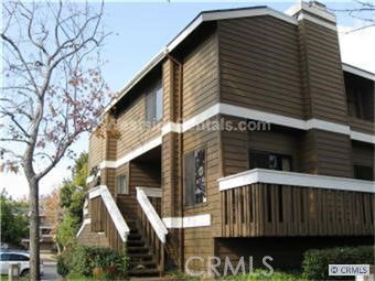 Front view of a two-story wooden house with stairs and balconies.
