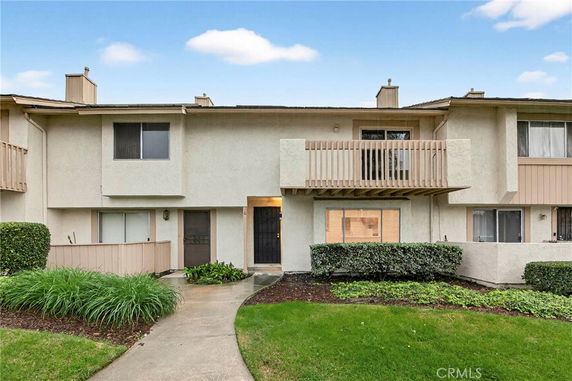 Front view of a two-story townhouse with small balcony and front door entrance.