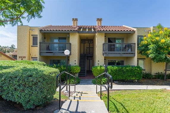 Front view of a two-story apartment building with balconies and a tiled roof.