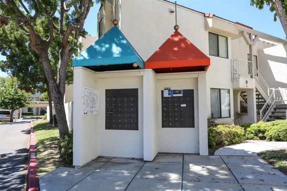 View of an apartment building with a mailbox area covered by colorful awnings.