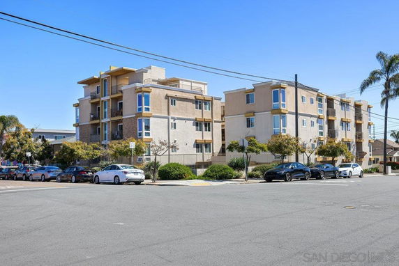 Street view of a multi-story apartment building with balconies and large windows.