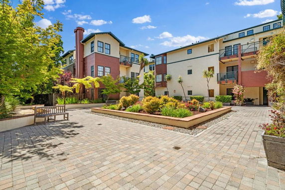 Front view of a multi-story residential building with balconies and landscaped courtyard.