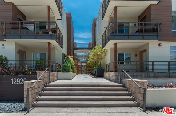 Front view of a multi-story apartment building with balconies and stair access.