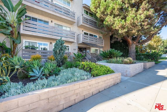 Front view of a multi-story residential building with balconies and landscaped entrance.