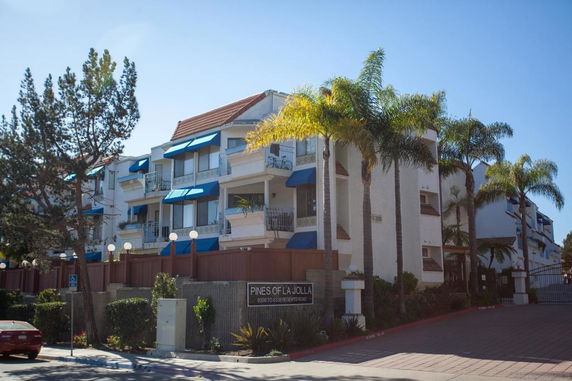 Front view of a multi-story residential building with blue awnings and balconies.