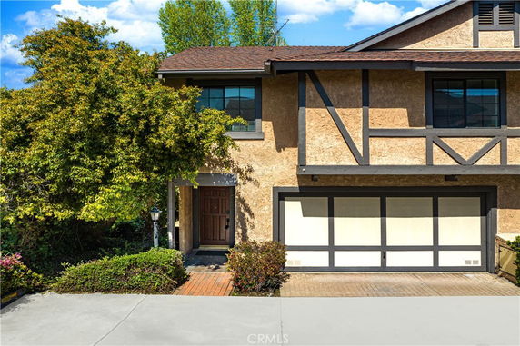 Front view of a two-story house with a large garage and a Tudor-style design.