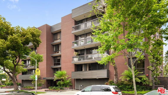 Front view of a multi-story brick apartment building with balconies.