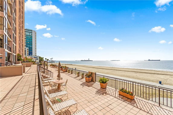 Deck area adjacent to a beachfront building with chairs and umbrellas.