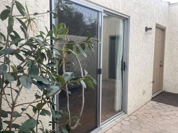 View of a building exterior featuring a sliding glass door and textured walls.