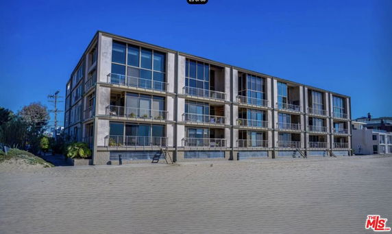 Front view of a multi-story beachfront building with large windows and balconies.