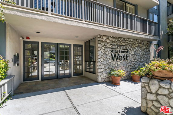Front entrance of a building with stone facade and potted plants.